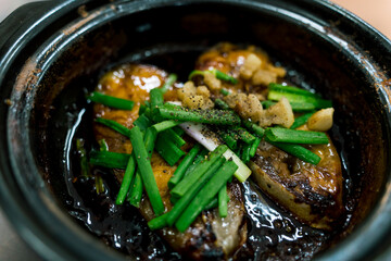 Close up Vietnamese Fish simmered with Caramel Sauce. Delicious Vietnamese clay pot fish with sauce, onion, greaves,chilies and herbs