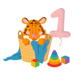 A cute baby tiger cub sits in a wicker basket surrounded by cubes and a pyramid. Number one in the form of a balloon. Concept for baby products in the first months of life.