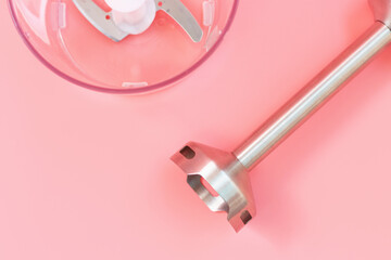 Steel hand blender and the bowl on pink background close-up, top view.