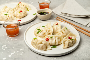 Dumplings Jiaozi Gyoza steamed on white plates with soy sauce and chili sauce. Food Takeout takeaway, home delivery