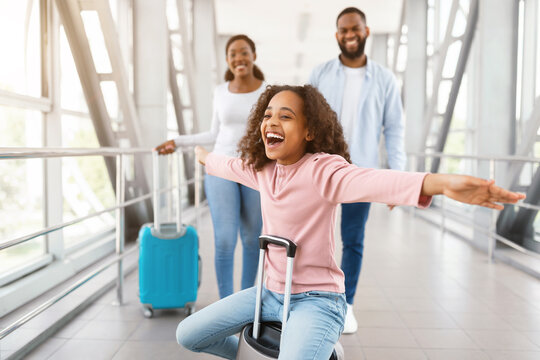 Happy black family traveling with daughter, having fun in airport