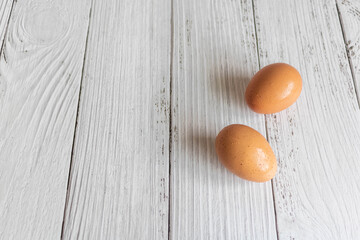 Brown chicken eggs lay on the wooden floor.