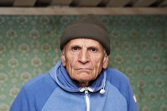 Portrait Of Old Angry Man With Wrinkled Face Wearing Knitted Cap