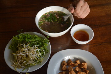 Top view of man eating authentic Lao Tapioca Chicken Noodle Soup or Khao Piak Sen 
