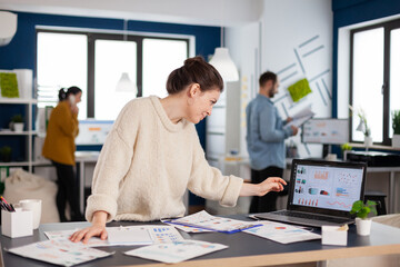 Business analyst working on new financial strategy looking at laptop display. Executive entrepreneur, manager leader standing working on projects with diverse colleagues. Successful corporate