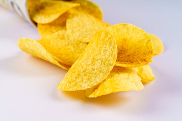 Closeup view of delicious crispy potato chips in package or can spill out on the table