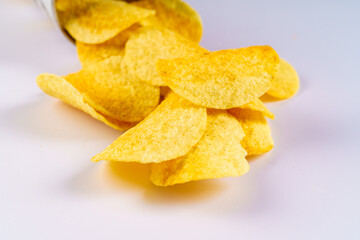 Closeup view of delicious crispy potato chips in package or can spill out on the table
