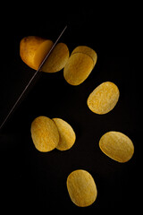 Close up of potato slice into potato chips isolated concept on black background with reflect shadow at bottom