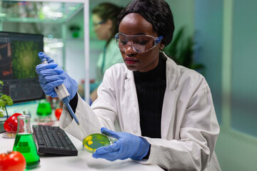 Biologist scientist african woman researcher taking genetic solution from test tube with...