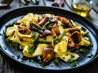 Pappardelle with mushrooms and asparagus on wooden table
