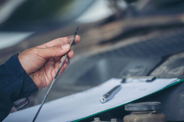 Car Mechanic man hand checking dipstick engine oil car mechanical on site service. Close up hand man check engine oil level Locate dipstick, wipe clean, check dipstick level before fill up engine oil