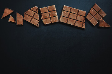Chocolate bars broken on dark background