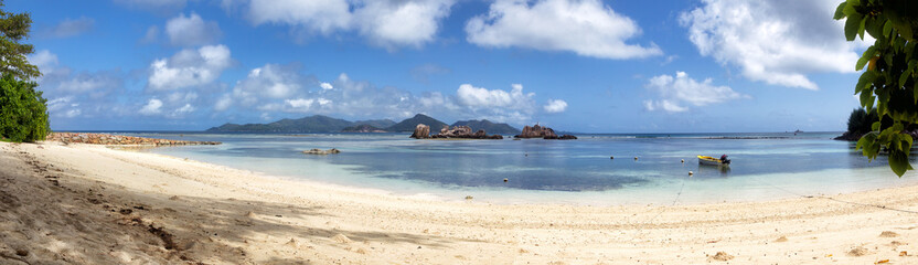 Lonesome tropical beach on La Digue, Seychelles, with view towards the neighbour island Praslin.