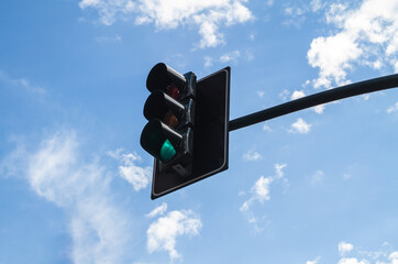 Green traffic light against blue sky.