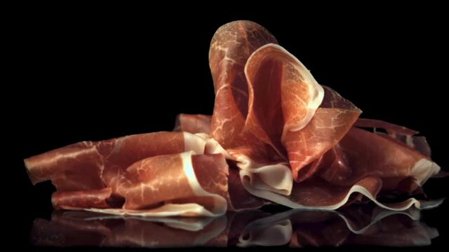 Super slow motion pieces of fragrant Spanish ham fall.Filmed at 1000 fps. On a black background. 