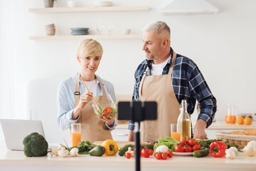 Couple cook together, explain recipe and record video for vlog and social media with smartphone camera and tripod