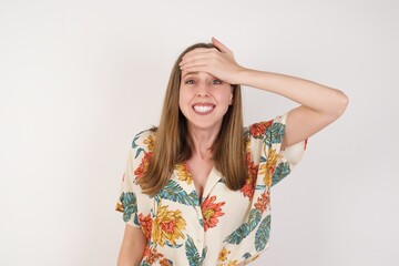 Oops, what did I do? Beautiful blonde woman holding hand on forehead with frightened and regret expression. Wearing casual clothes standing outdoors.