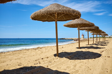 straw umbrellas on the characteristic beach of Erice mare Trapani with clear sea waiting for the beginning of summer