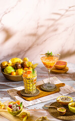 Bright food photography of tropical cocktails with natural juice. Backdrop with a basket with passion fruit, maracuya, physalis, orange, dragon fruit and lemon.