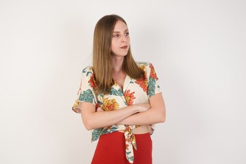 Image of upset pretty young caucasian lady standing indoors with arms crossed. Looking with disappointed expression aside after listening to bad news. Confident girl.