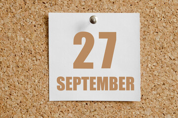 september 27. 27th day of the month, calendar date.White calendar sheet attached to brown cork...