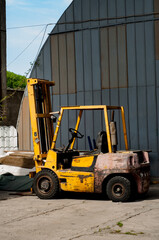 Forklift Truck on Background of a Metal Wall of a Store Warehouse. Yellow Old Forklift at a Construction Site.