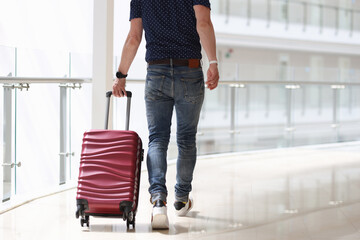 Fototapeta na wymiar Man is rolling suitcase in hotel corridor