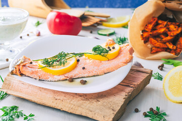 Baked salmon on a bright background. Salmon with vegetable side dishes.
