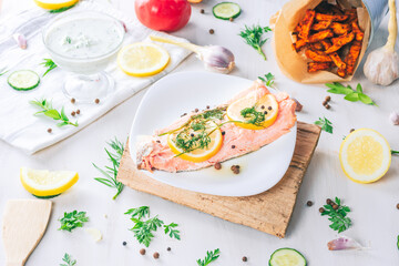 Baked salmon on a bright background. Salmon with vegetable side dishes.
