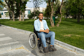 Accessible environment for disabled people concept. Happy black guy in wheelchair going down ramp...