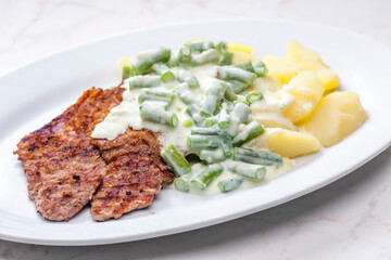 pork meat with cream sauce of green beans and cooked potatoes