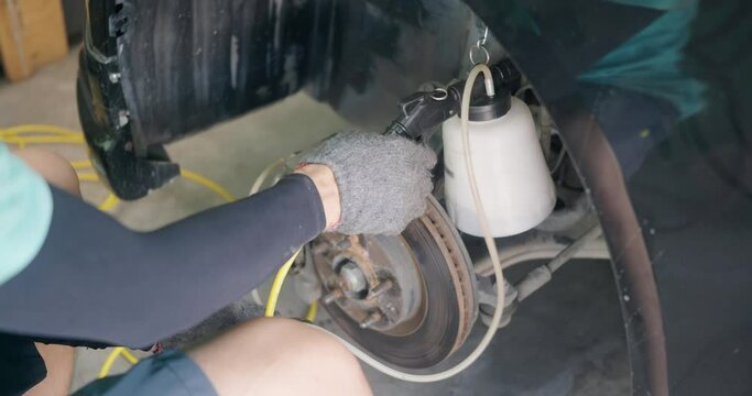 Auto mechanic replacing brake fluid on a vehicle, technician bleed air out of disc brake system in garage workshop, Car repair in a car service