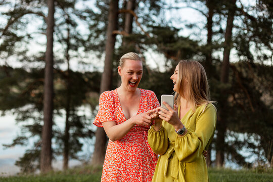 Smiling female friends using smart phone