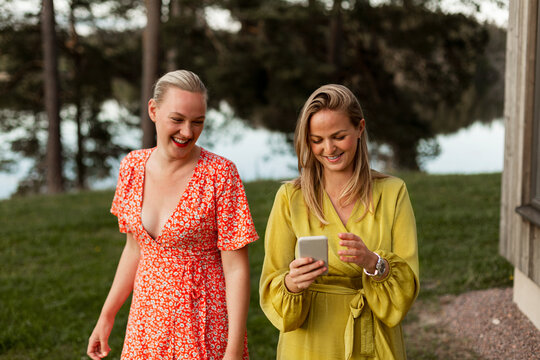 Smiling female friends using smart phone