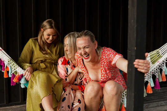 Smiling female friends sitting in hammock