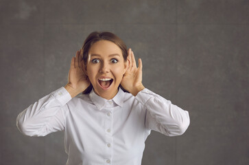 Young business lady learns great amazing news. Happy excited curious woman listening with hands at...