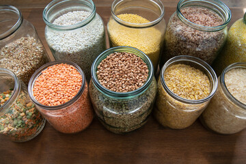 cereals in glass jars. legumes, peas, buckwheat, rice, burlap, barley, lentils, red lentils.