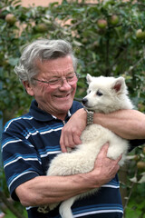 Glücklicher Senior hält Deutscher Mittelspitz Hund Welpe auf dem Arm
