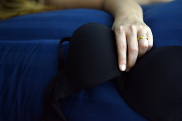 Relax time after work, Black bra in woman hand sleeping with blue bed.