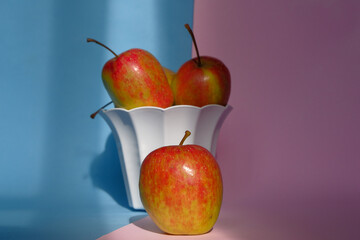Photo of an apple in a container on a pink and blue background
