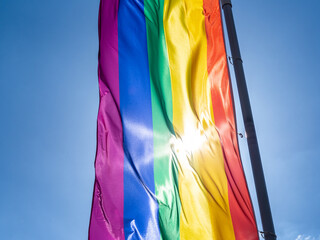 Rainbow flag in sunshine against blue sky