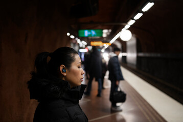 Woman with earphones standing at metro station