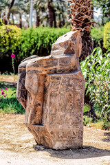 A broken Ancient Egyptian Statue hieroglyphics on its base.