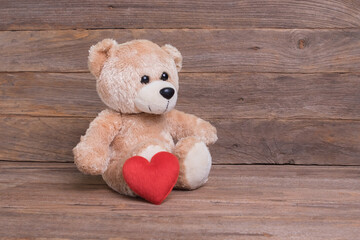 Teddy bear with heart sitting on wooden floor