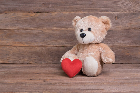 Teddy bear with heart sitting on wooden floor