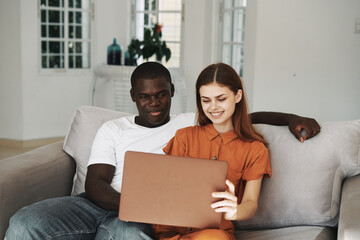 young couple at home on the couch in front of laptop