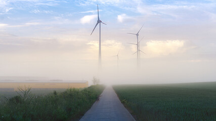 Windkraft Anlage mit zartem Nebel und Wolken im Hintergrund, mit Freiraum für eigenen Text.