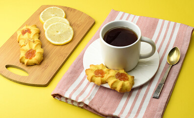 White cup of tea, homemade cookies, sliced lemon, kitchen napkin, tea spoon. Afternoon, dessert, tea party concept. Side and top view.