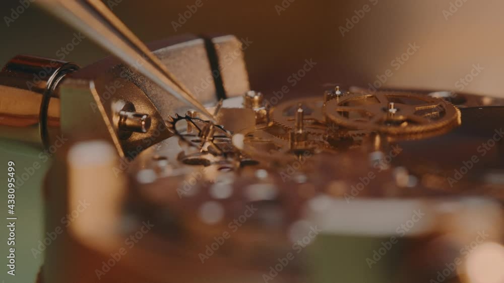 Poster watchmaker assembling the machine of a watch using a tweezer - macro shot