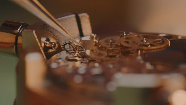 Watchmaker Assembling The Machine Of A Watch Using A Tweezer - macro shot